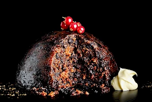 Photograph of Whole Christmas pudding with slice out, cream dollop and redcurrants