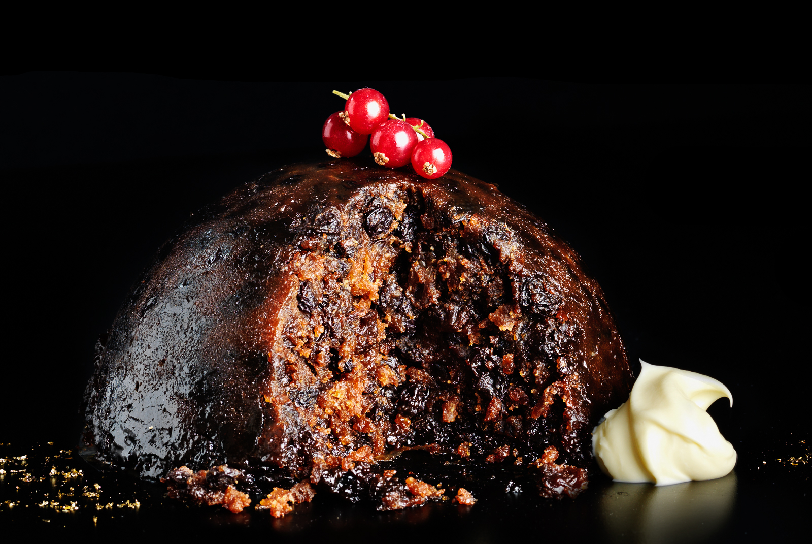 Photograph of Whole Christmas pudding with slice out, cream dollop and redcurrants