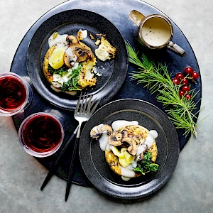 Photograph of two plates of ricotta stack with mushrooms, leeks and kale with a creamy sauce