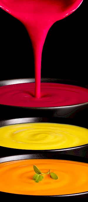 Photograph or bowls of soup with pan pouring liquid