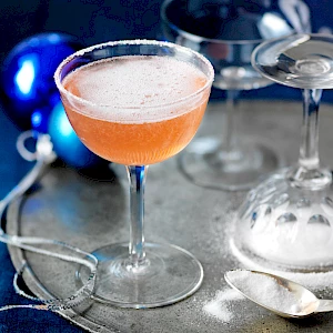 Photograph of a Sugar Plum Fizz Cocktail with salt rim and blue baubles