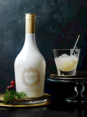 Photograph of glass of egg nog and bottle of egg nog cream